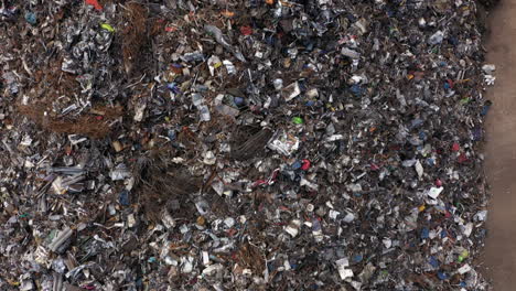 aerial drone footage over a large heap of scrap metal waiting to be loaded onto a ship for recycling