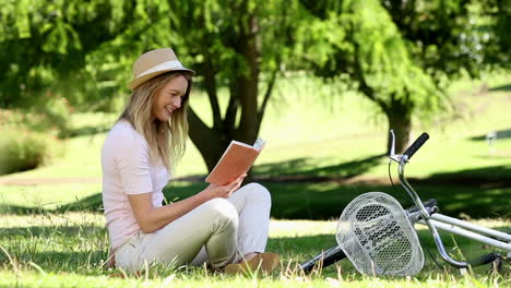 Niña-Bonita-Leyendo-Junto-A-Su-Bicicleta-En-El-Parque