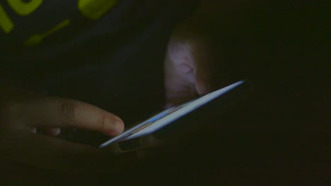 persona que utiliza un teléfono inteligente en la oscuridad