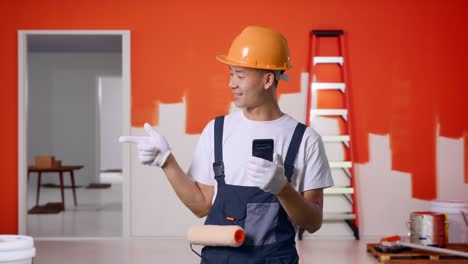 contratista sonriente usando un teléfono inteligente en el sitio de trabajo