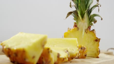 primer plano de una piña cortada por la mitad en una tabla de cortar
