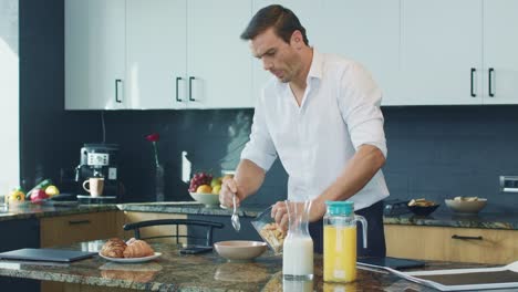 hombre de negocios preparando el desayuno en la cocina. profesional comprobando teléfono móvil.