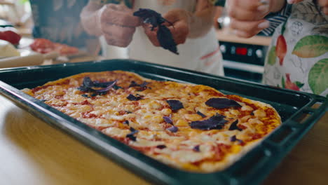 close-up of adding basil leaves to freshly baked homemade pizza