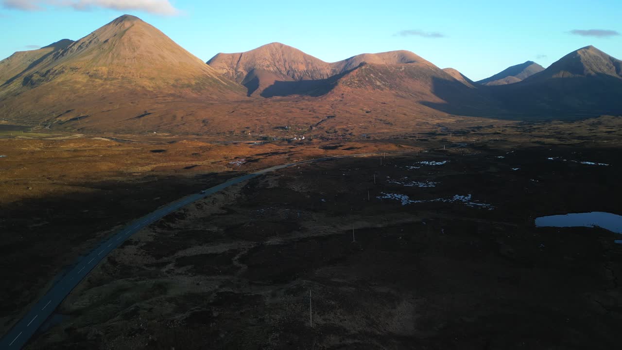 Elevating shot revealing highland road and Red Cuillin mountains lit by sunrise at Sligachan on the Isle of Skye Scotland