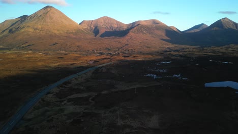 elevating shot revealing highland road and red cuillin mountains lit by sunrise at sligachan on the isle of skye scotland