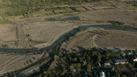 vista aérea del río aragvi por el pueblo y el vasto paisaje en georgia - disparo de dron ascendente