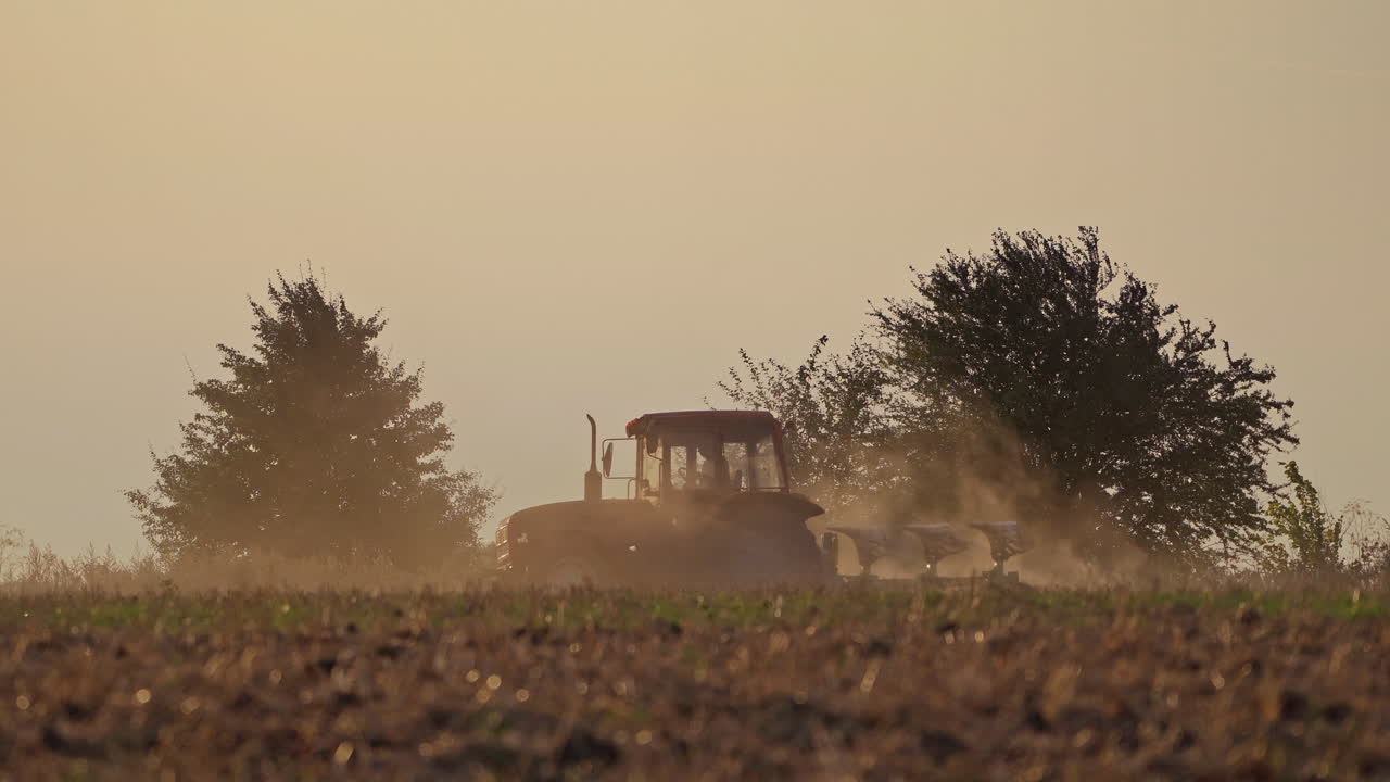 Tractor working on the field in the evening. Agricultural works on the natural background in the countryside.