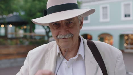 portrait d'un homme âgé élégant en vacances touriste à l'air joyeux portant un costume blanc et un chapeau enlevant des lunettes