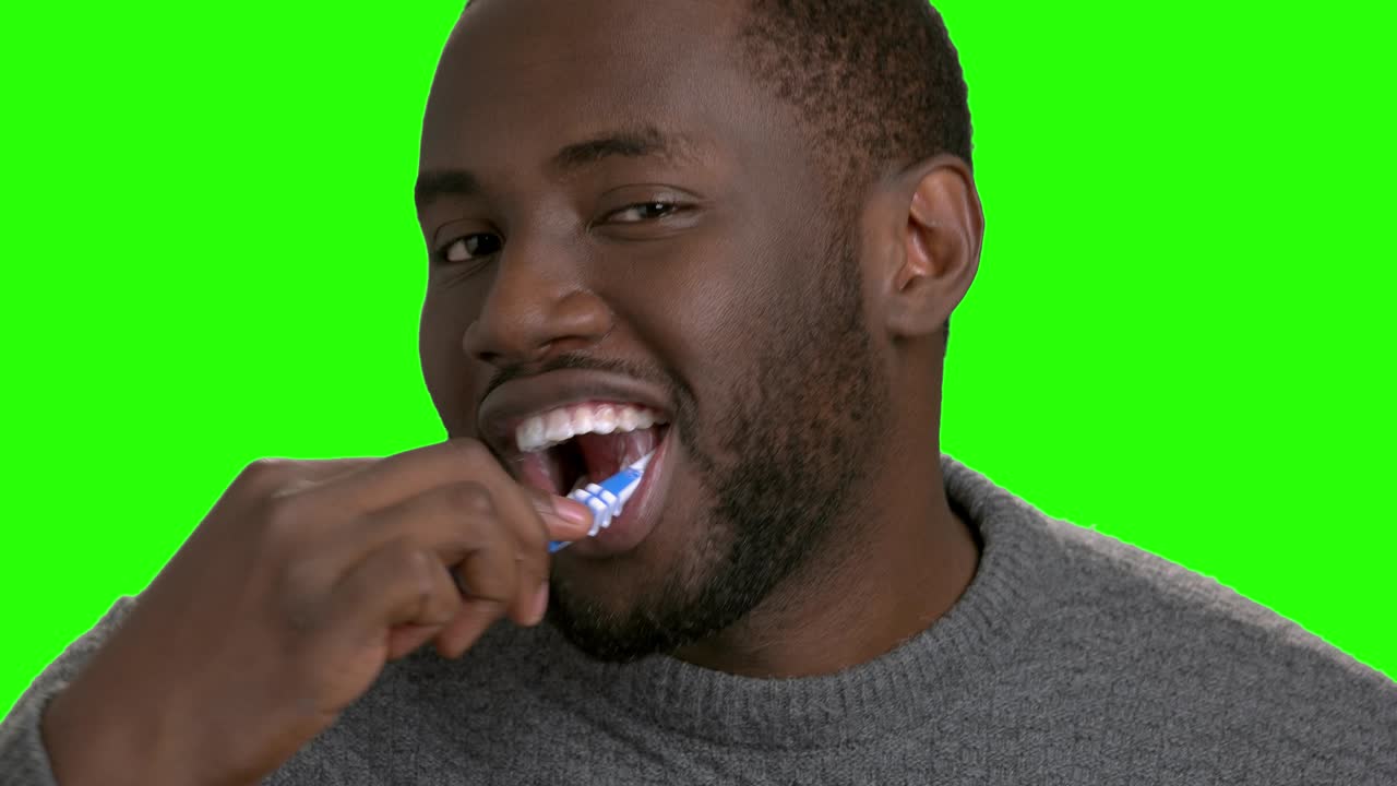 Dark-skinned man brushing his teeth.