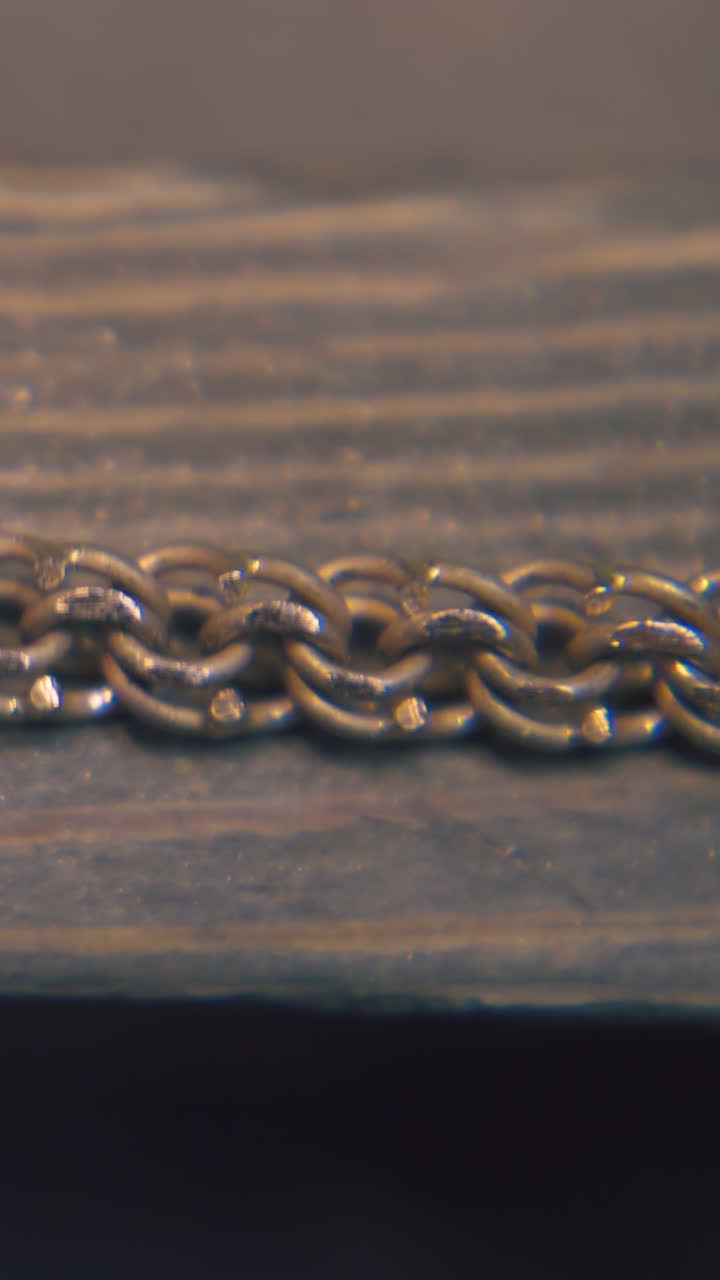 CU: professional goldsmith grinds beautiful gold chain with rasp on wooden part in jewelry workshop extreme close view