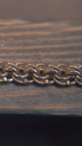 cu: professional goldsmith grinds beautiful gold chain with rasp on wooden part in jewelry workshop extreme close view