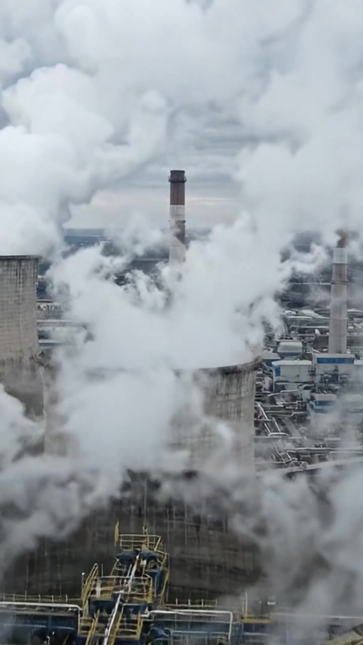 Industrial Cooling Towers Emitting Steam in a Power Generation Facility Surrounded by Dense Clouds of Vapor in an Urban Landscape