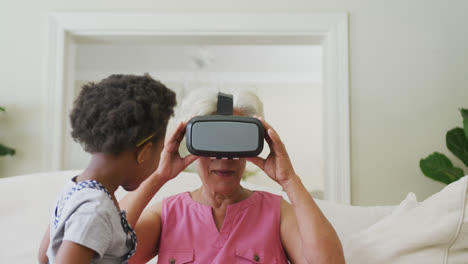 abuela afroamericana feliz usando auriculares vr con su nieta en la sala de estar