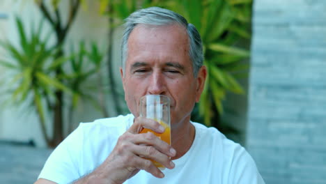 retired man drinking orange juice outside