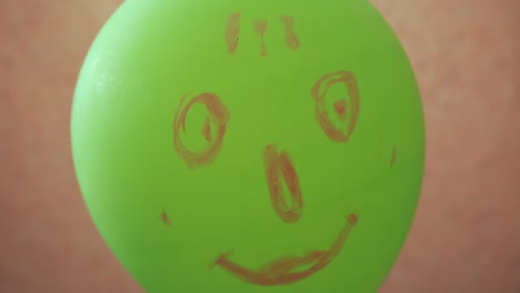 una cabeza divertida y verde hecha de un globo mira a la cámara. un chiste, una cara divertida dibujada.