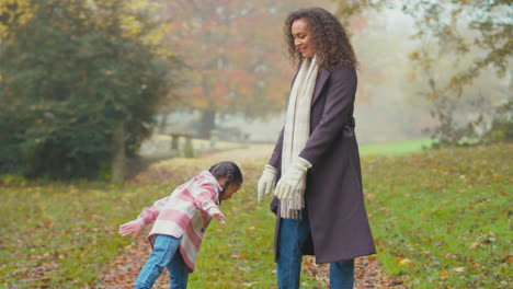 mother and daughter having fun on walk in autumn countryside balancing on one leg