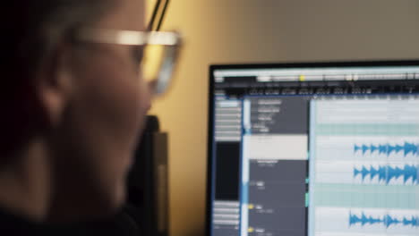 Female-producer-sits-in-front-of-a-monitor-and-listens-to-recorded-music