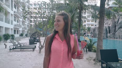 beautiful girl walks around hotel near tall green palms