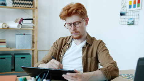 young designer working on digital tablet in home office