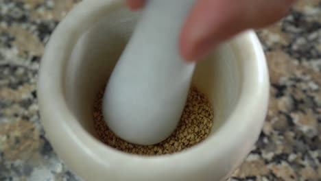 grinding toasted sesame seeds in a marble pestle and mortar. close up.