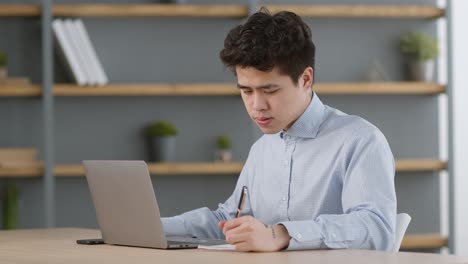 노트북을 사용하고 메모를 하는 사람