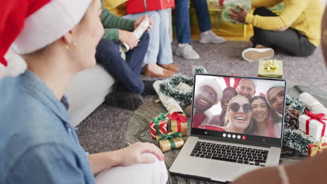 diverse friends with santa hats having laptop video call with happy diverse friends