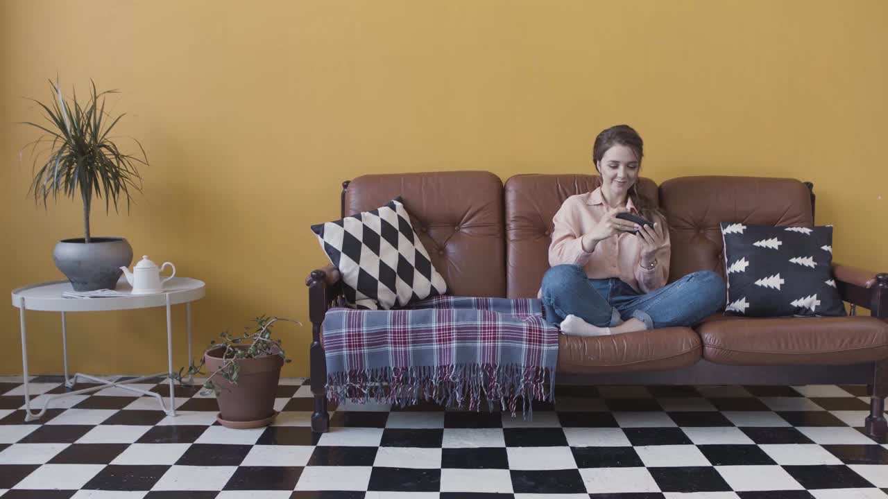 mujer relajándose en un sofá, usando el teléfono