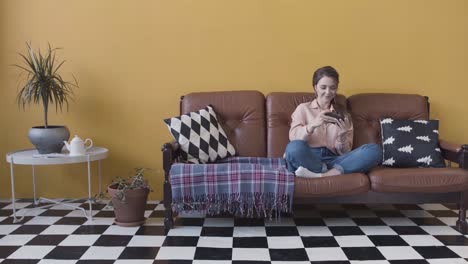 woman relaxing on a sofa, using phone