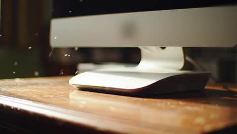 a close-up of a computer on a wooden desk with sunlight streaming through, capturing dust particles dancing in the air, showcasing a calm workspace atmosphere