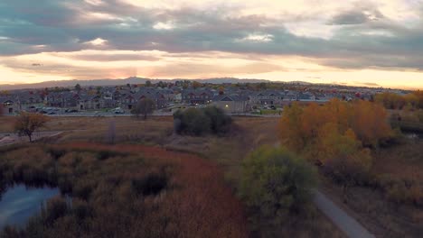 Drone-flight-over-a-tree-near-a-pond-facing-the-Rocky-Mountains-in-Colorado