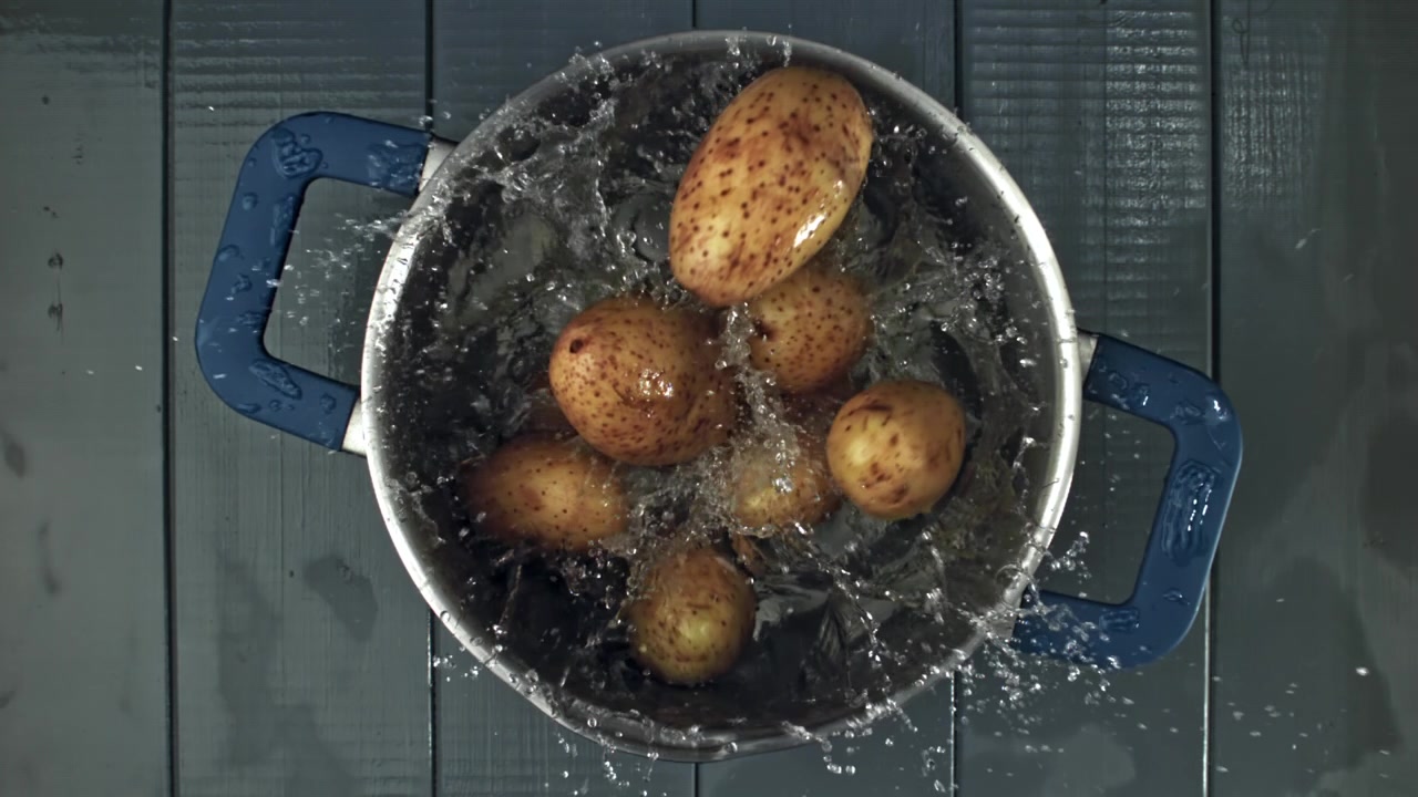 Patate fresche che schizzano nell'acqua in una pentola