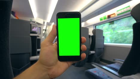 mano sosteniendo un teléfono con una pantalla verde en el tren