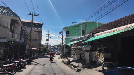 view from a songthaew driving through the streets of koh tao, thailand, showcasing motorcycles, shops, and vibrant local life.