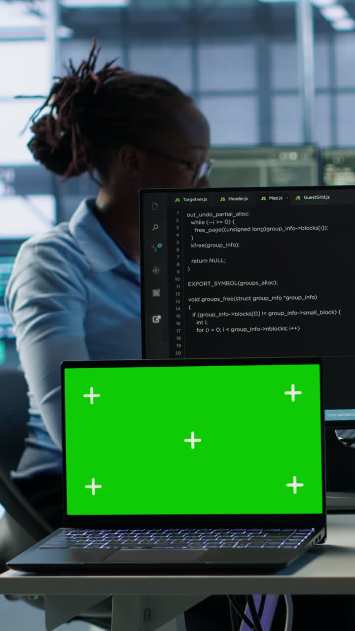 Bærbar computer med grøn skærm og programmør, der arbejder med kode
