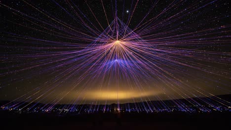 a stunning display of colorful light trails creating a vibrant geometric pattern against the night sky filled with stars and a soft glowing horizon