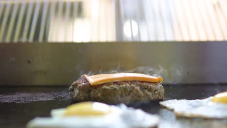 Placing-cheese-on-a-smoking-grilled-burger-in-a-fast-food-window-shop