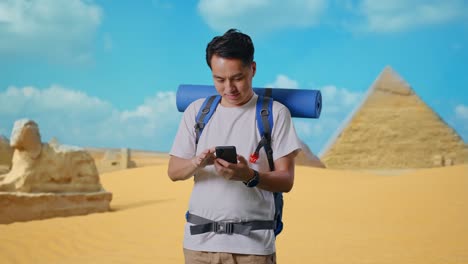 asian male hiker with mountaineering backpack enjoy using smartphone while traveling in pyramid of giza