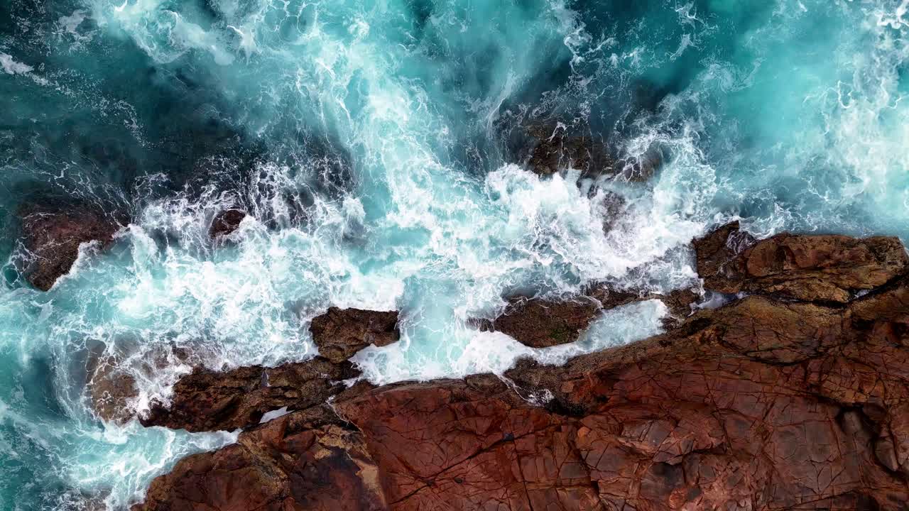 una vista a volo d'uccello di una costa rocciosa con le onde che si infrangono sulle rocce e sull'oceano