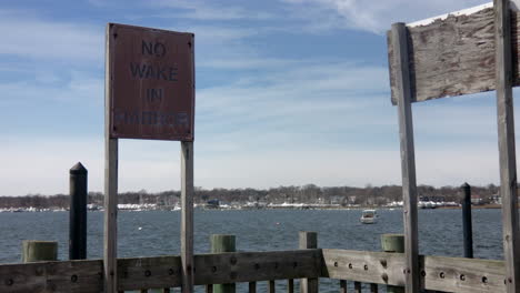 pan to old, weathered no wake in harbor sign on pressure treated wood deck