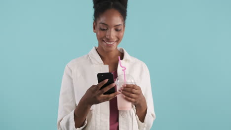 smiling woman with phone drinking milkshake