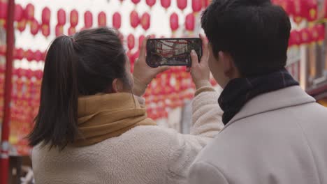 Pareja-Asiática-De-Vacaciones-Tomando-Fotos-En-Chinatown-En-Londres,-Reino-Unido-En-El-Teléfono-Móvil