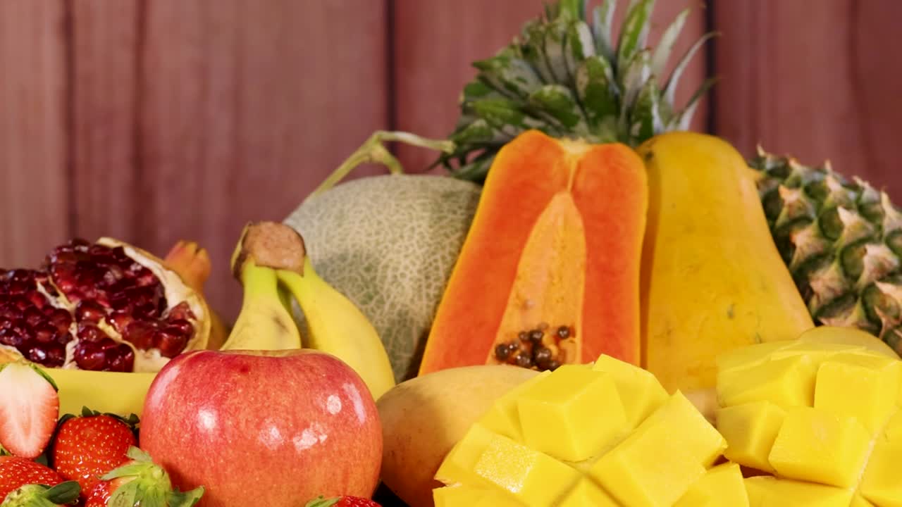 A vibrant arrangement of papaya, pineapple, mango, and more on a rustic wooden backdrop.