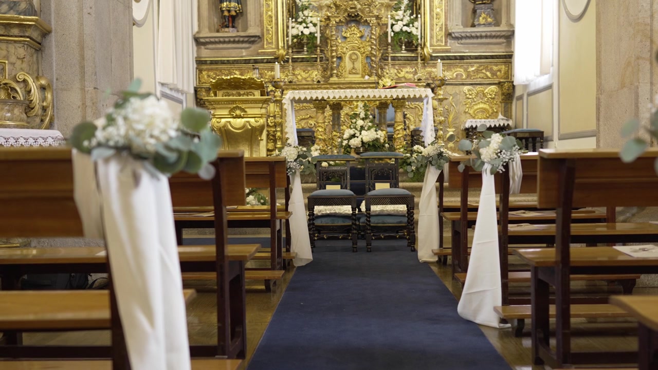 Navata della chiesa decorata con un tappeto blu che conduce a un altare adornato d'oro con composizioni floreali