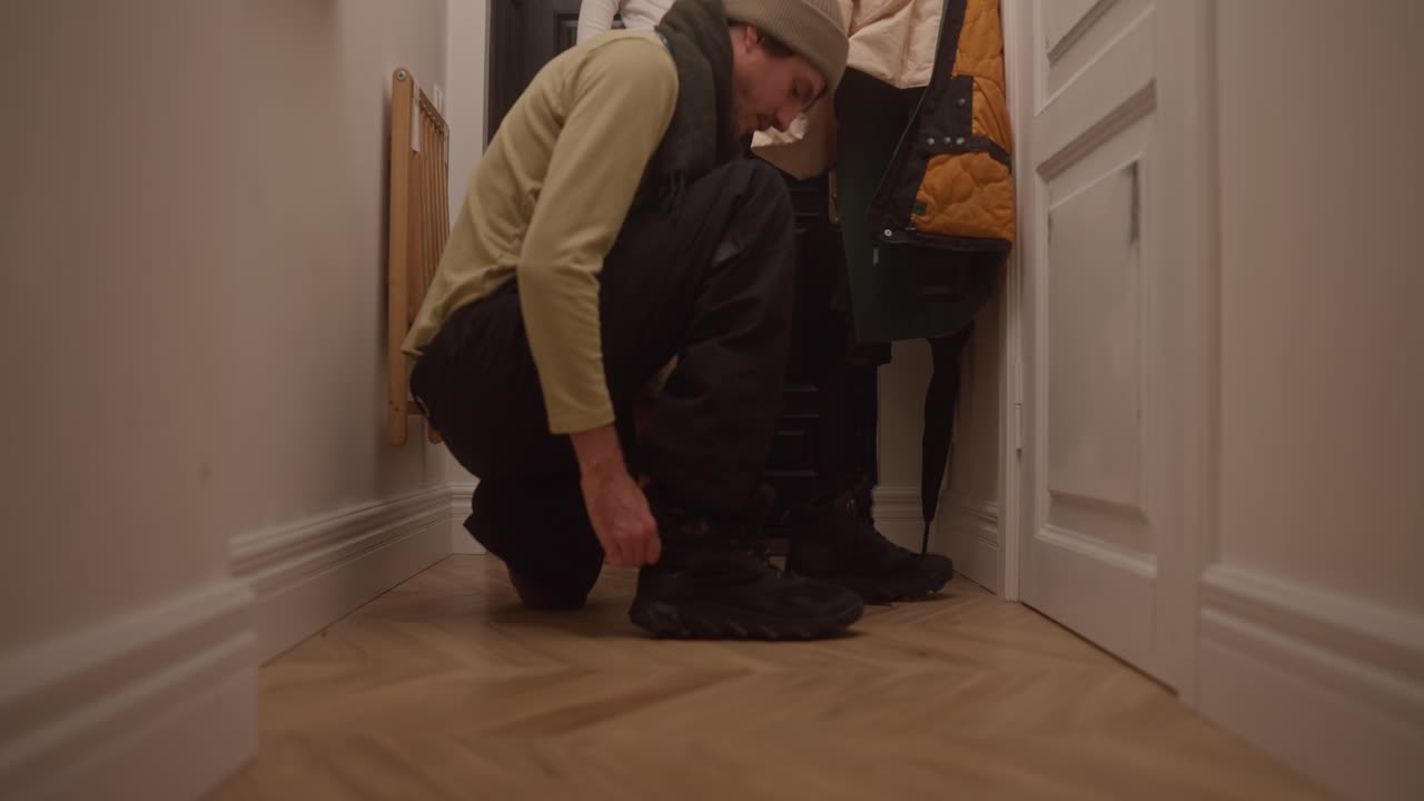 Man tying his shoes in a hallway
