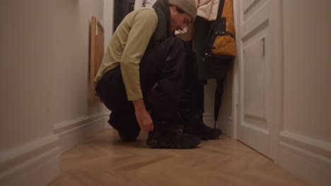 man tying his shoes in a hallway