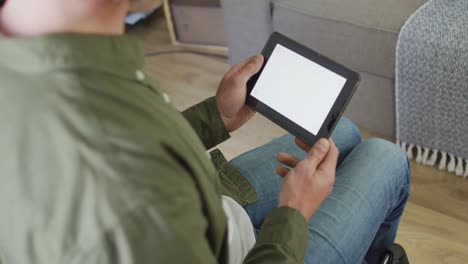 Caucasian-disabled-man-sitting-in-wheelchair-using-tablet-at-christmas