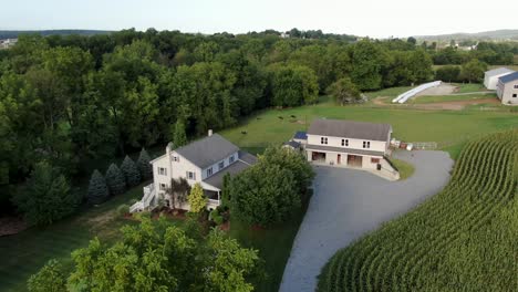new amish house and barn in lancaster county pennsylvania, home surrounded by farm fields and meadow pasture, aerial shot, gray two story home with shutters