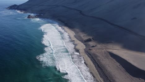 single road cuts across sandy mountain slope at beach in coastal chile