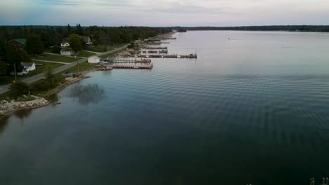 Aerial-fly-down-coastline-with-summerhouses-and-docks,-Lake-Huron,-Michigan