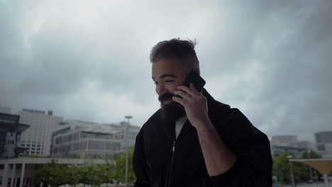 Cheerful-bearded-brunet-talking-on-phone-during-stroll.